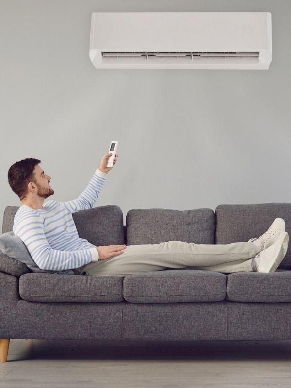 A man using a remote to change the temperature of his A/C