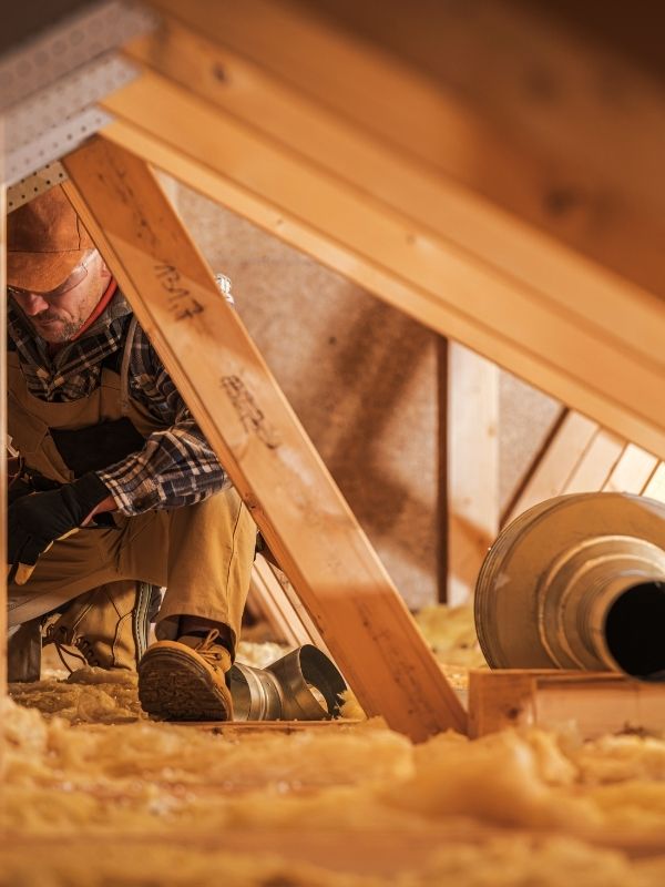 An HVAC technician working in an attic. 